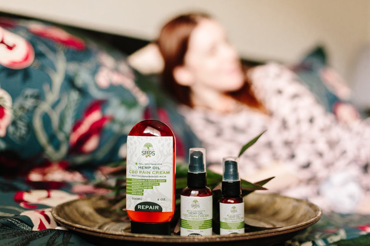 CBD hemp oil pain relief products displayed indoors with a relaxed person in the background.